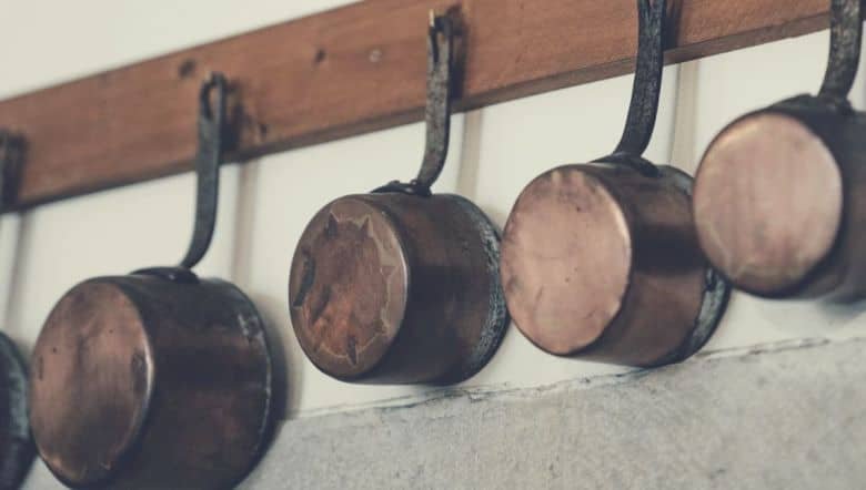 copper pots and pans hanging from a rack