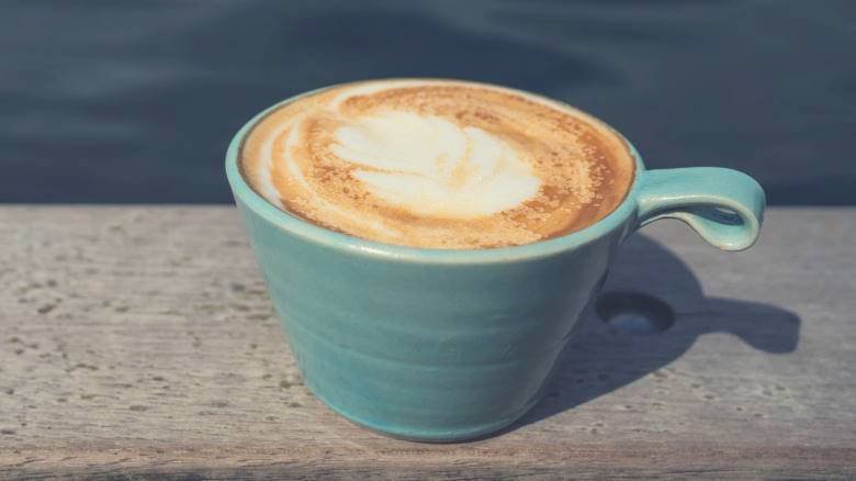 Cappuccino in a blue cup on a wooden bench