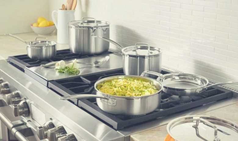 Many items of the Cuisinart MultiClad Pro cookware set on a home kitchen oven hob
