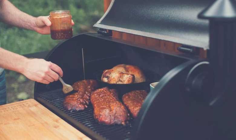 Different meats being basted on an open Traeger grill