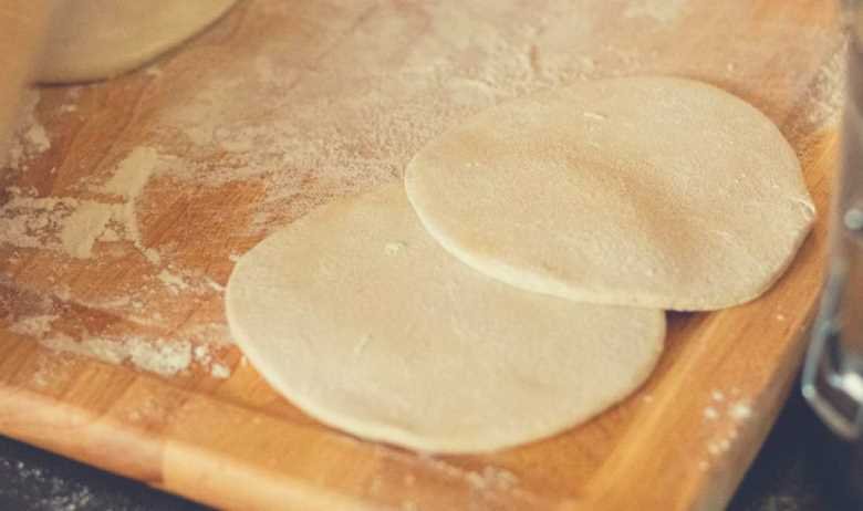 Two freshly prepared flour tortillas on top of each other on a wooden cutting board