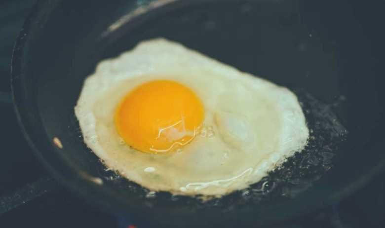 An egg frying in a cast iron skillet