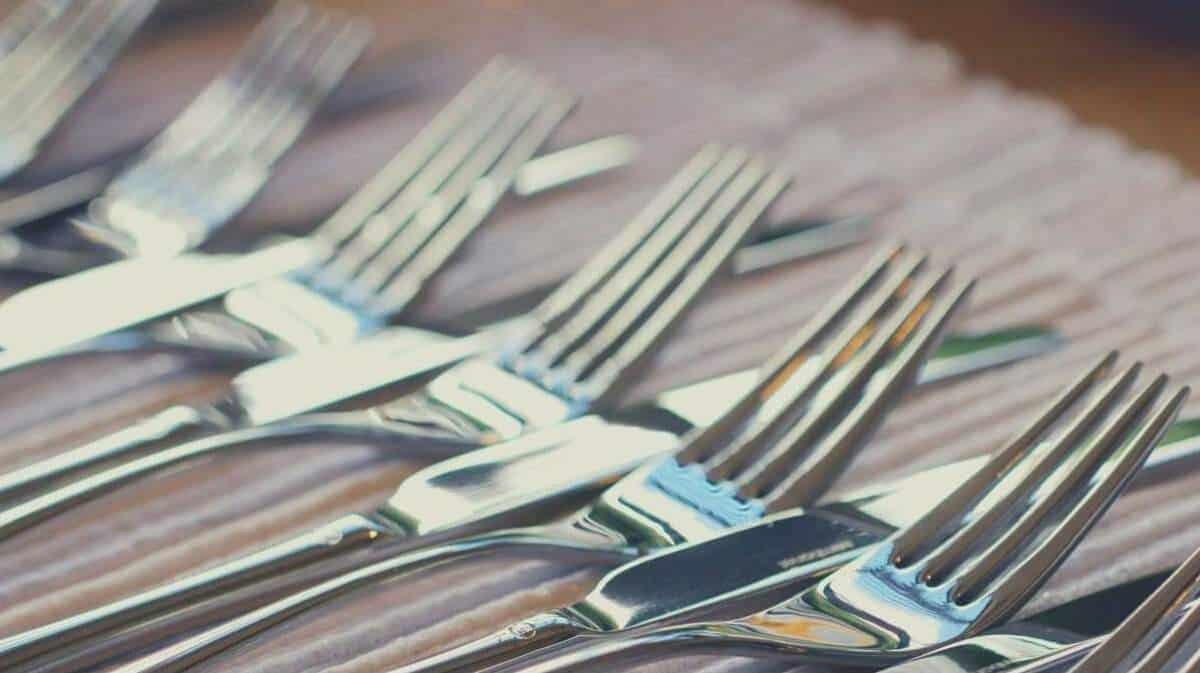 A close up shot of knives and forks laid out neatly on a table