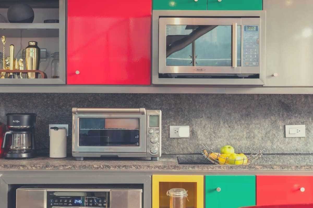 A brightly colored kitchen featuring an oven, convection oven and microwave on a shelf
