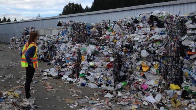 someone standing next to a pile of recycling materials