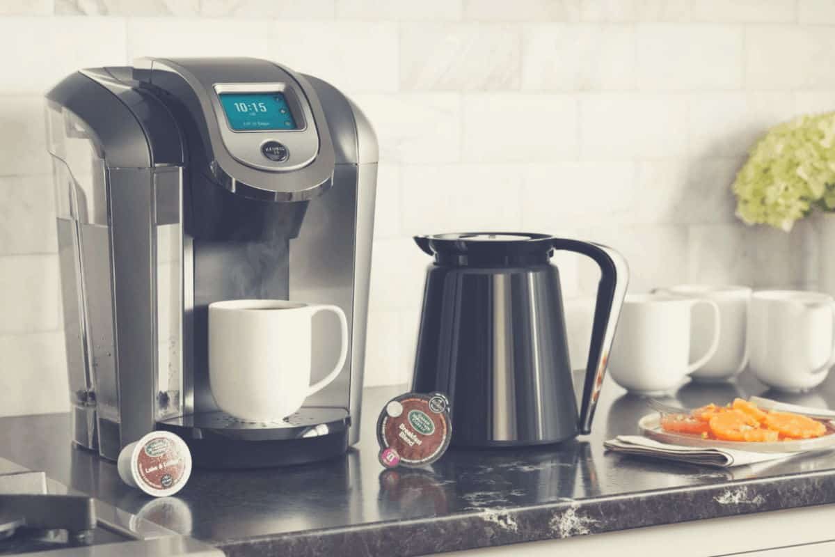 A promotional shot of the Keurig K475 with carafe and pods