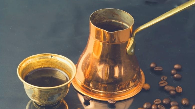 A picture of a brass cezve and cup