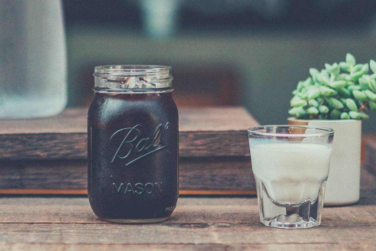 a glass of milk next to a mason jar filled with cold brew coffee