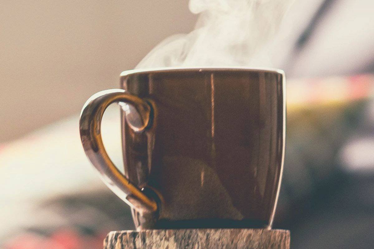 A steaming hot mug of coffee sitting on a coaster
