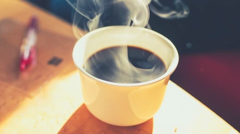 a steaming hot cup of coffee on a wooden table