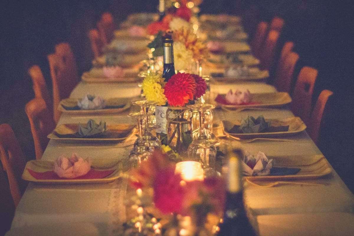 a shot of a long dining table with a bottle centrepiece