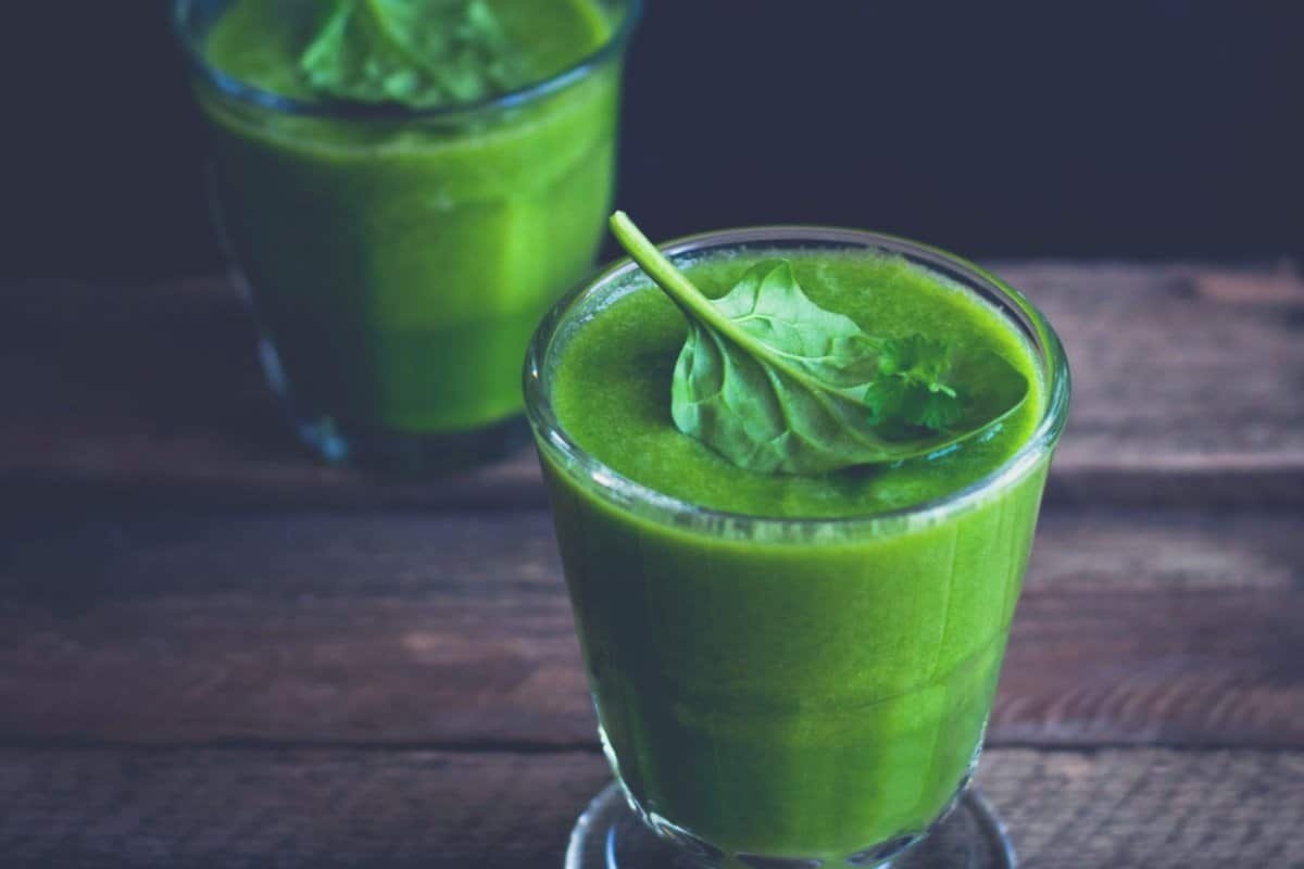 Two glasses full of green juice on a wooden countertop
