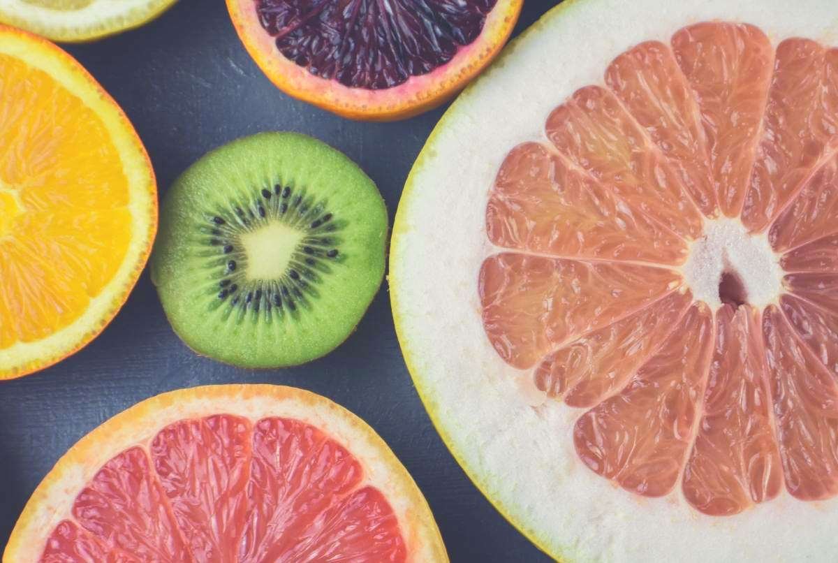 A close up shot of grapefruit, lemon and kiwi fruit on a chopping board
