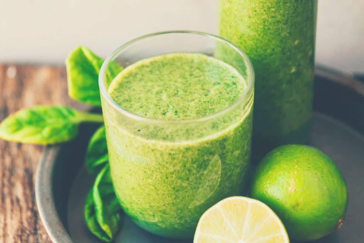 Limes, a green smoothie in a glass and a container of juice