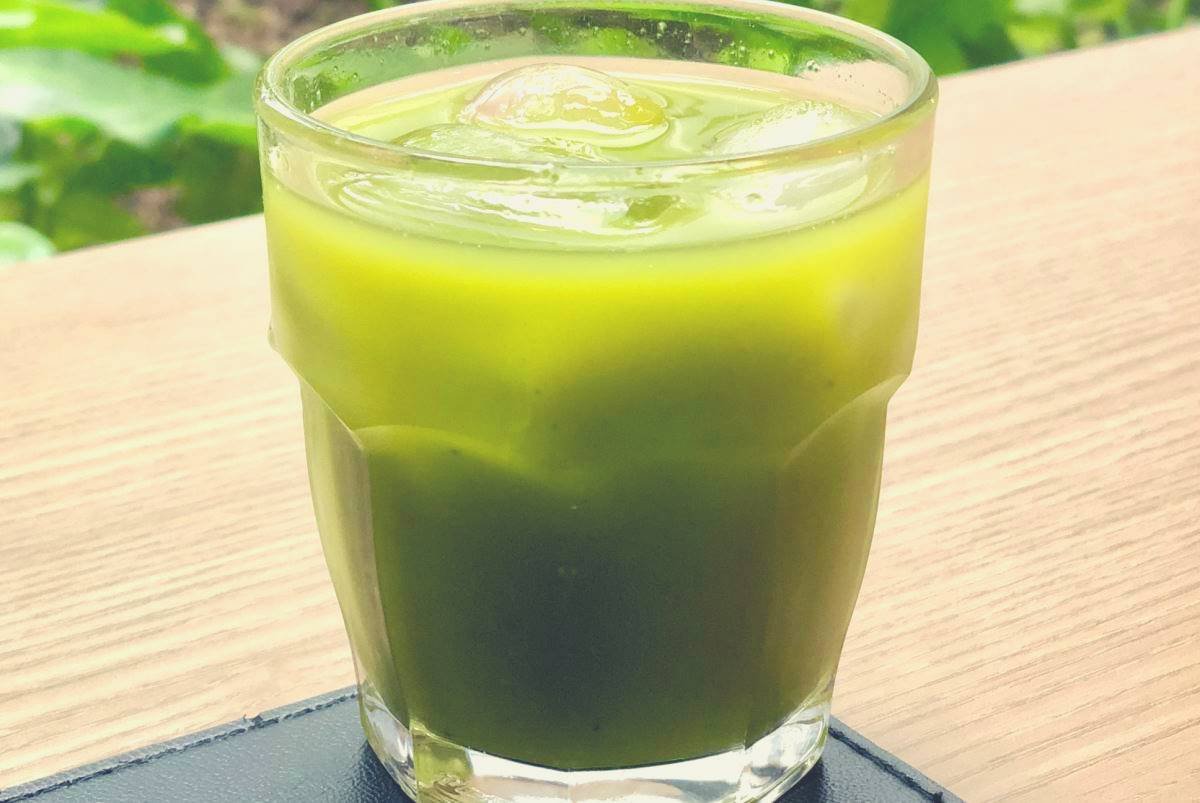 A green juice drink on a wooden table on a garden bench