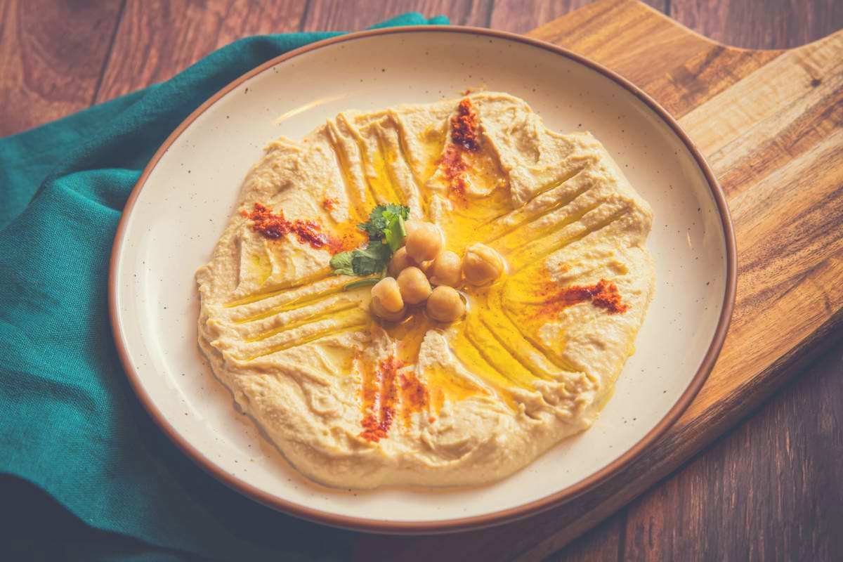 A pile of sticky hummus with chickpeas on a ceramic plate