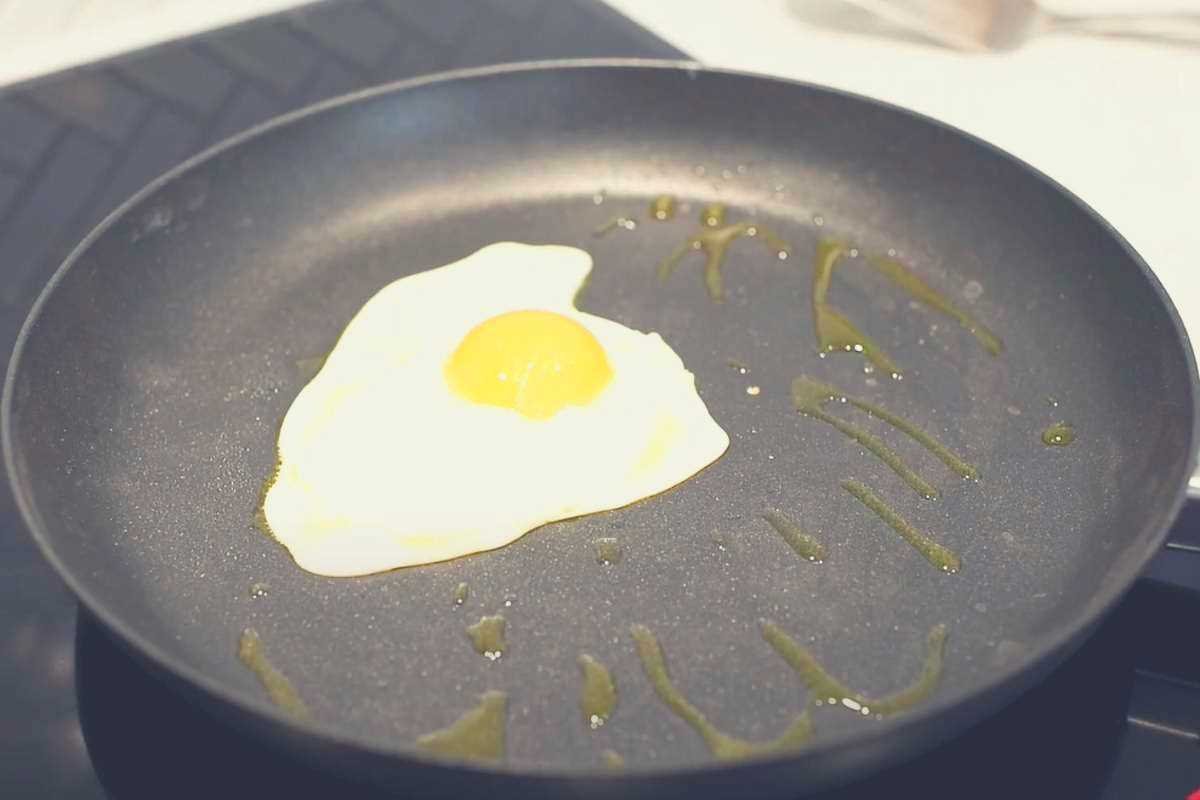A fried egg in a Scanpan with splashes of oil all over it