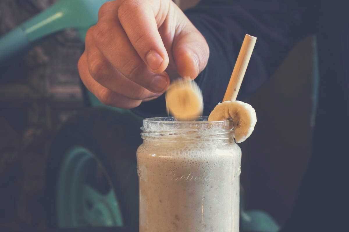 A protein shake in a mason jar, with two slices of banana pushed onto the rim