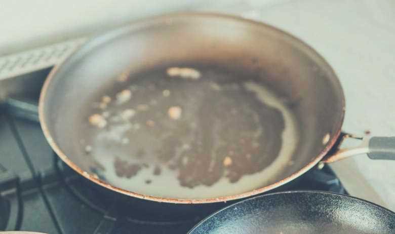 A greasy frying pan sitting on a gas stovetop