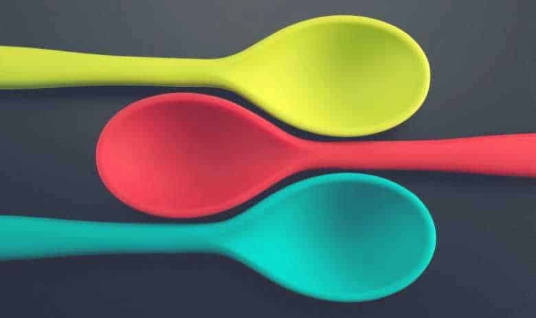three yellow, red and blue silicone cooking utensils laid down above one another
