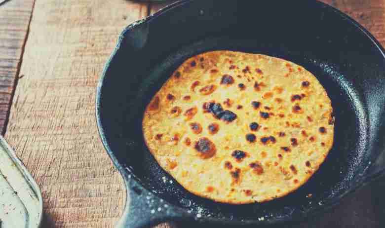 A crepe in a cast iron skillet which is sitting on a wooden kitchen countertop