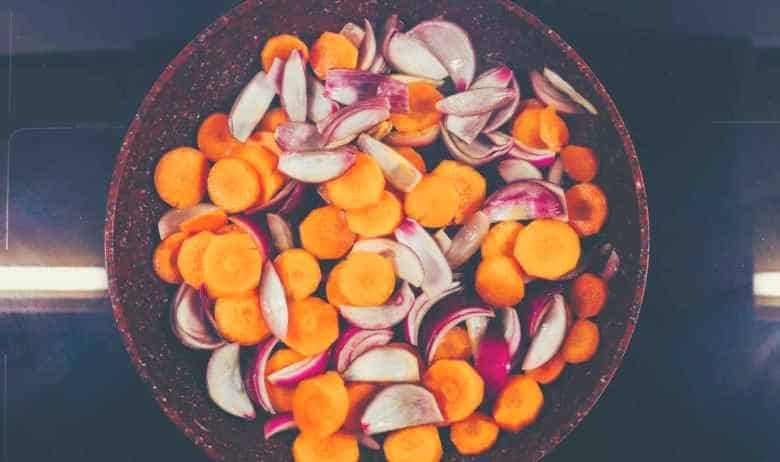 Carrots and onions cooked in a frying pan on top of an induction cooking surface