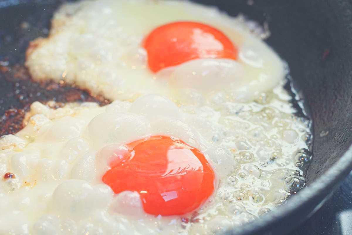 Two eggs frying sunny side up in a cast iron skillet