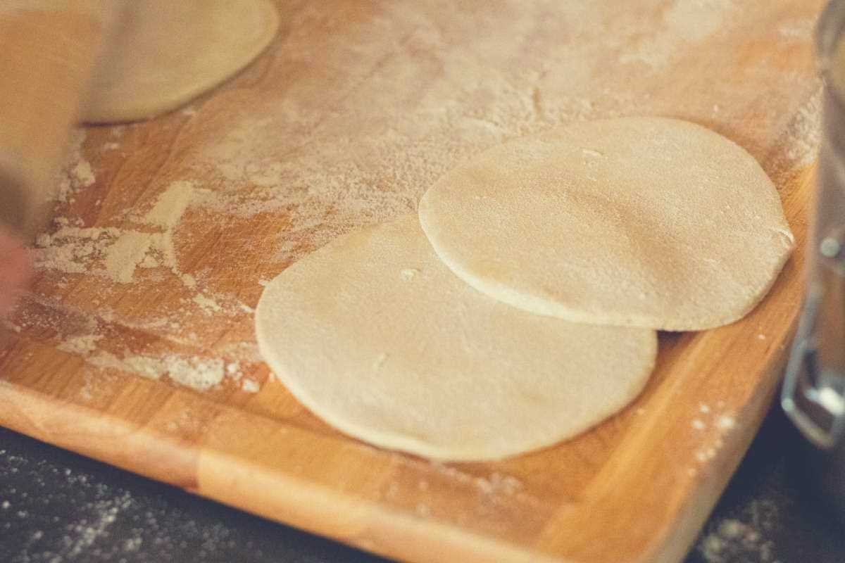 Two freshly rolled out flour tortillas on a wooden cutting board