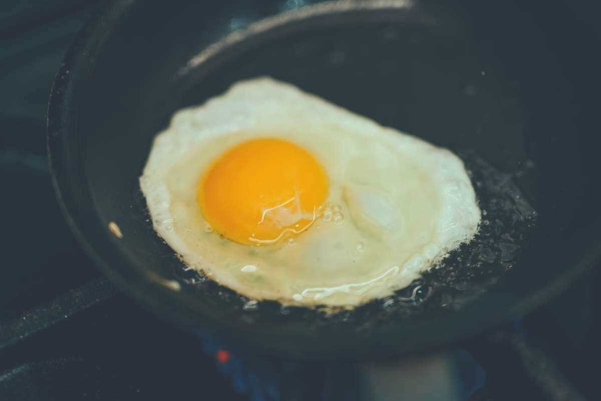 A single egg frying in oil in a skillet