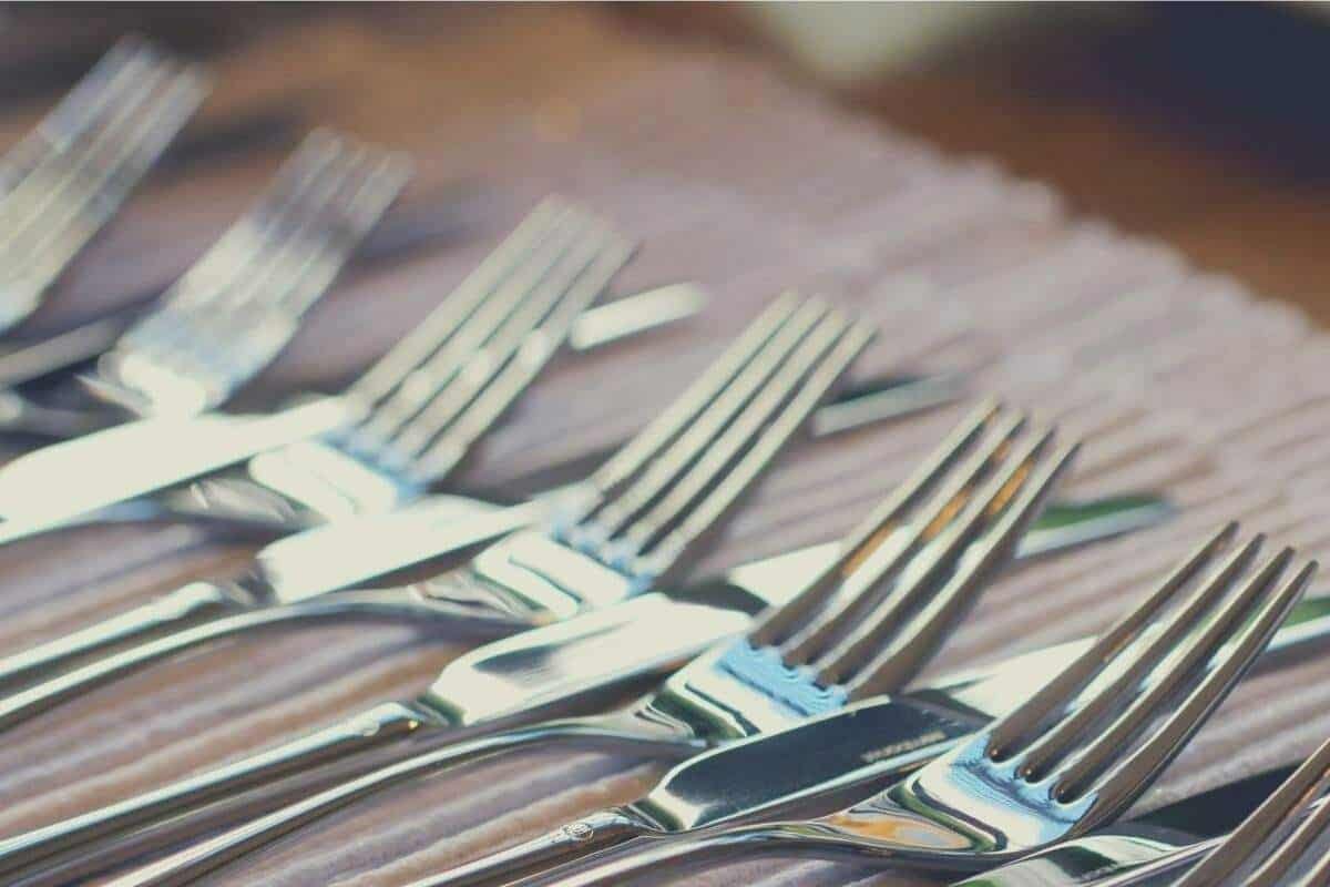 A selection of knives and forks laid out neatly on a tablecloth
