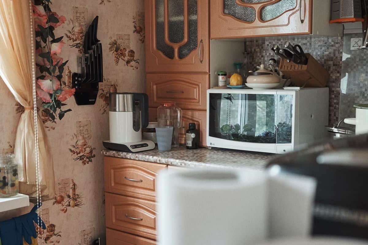 A country kitchen featuring wooden cabinets and a microwave on a countertop