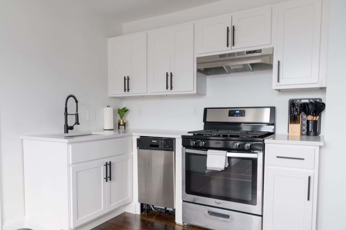 A small apartment kitchen with faucet, oven, dishwasher and cupboard spaces.